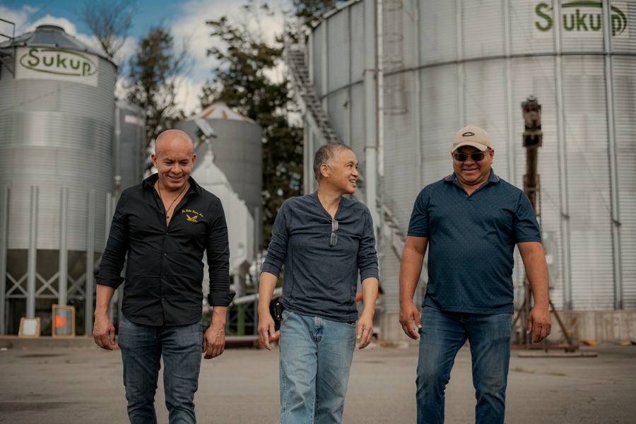 Three farmers walking between grain silos
